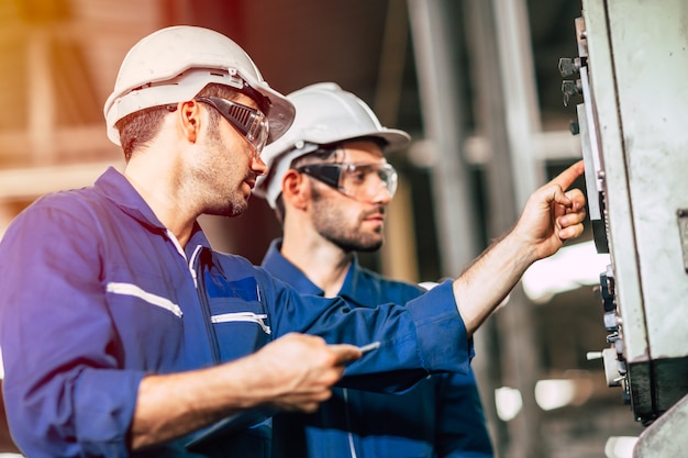 Photo industry engineer team worker teaching help friend operate control heavy machine in factory