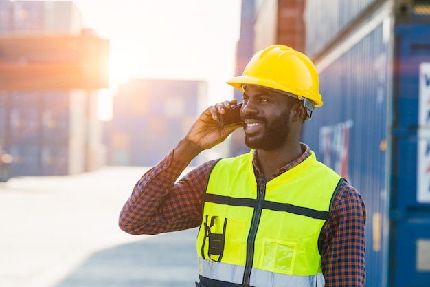 Lavoratore di sesso maschile dell'industria che utilizza il cellulare chiamando le persone di contatto con un sorriso felice buona espressione