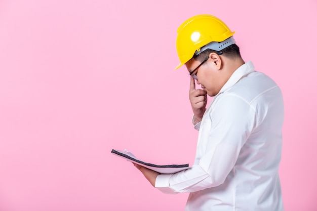 Industry worker or engineer working an architect builder studying layout plan serious civil engineer working with reading on blueprint isolated on pink blank copy space studio background,indoor studio