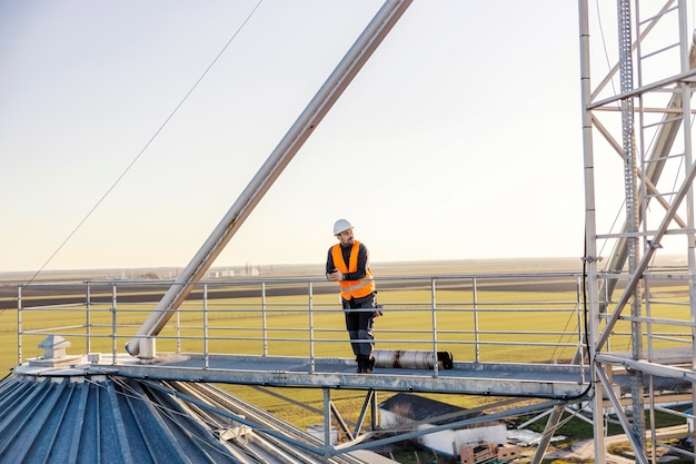 An industry worker standing on top of the silo and taking a break