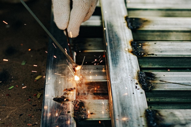 Photo industry worker wearing white glove and welding iron at work outdoor closeup hand tool for welding steel concept industrial using welding machine for construction