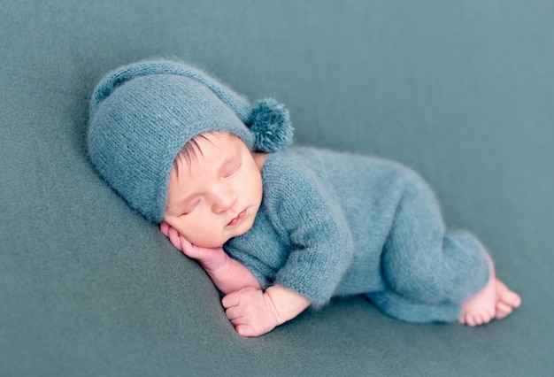 Infant baby boy sleeping in woolen costume with bare feet