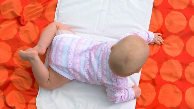 Infant baby girl, top view. Cute baby girl lying on her stomach. Babyhood and innocence.