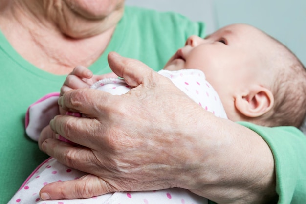 The infant on hands at her great-grandmother close-up