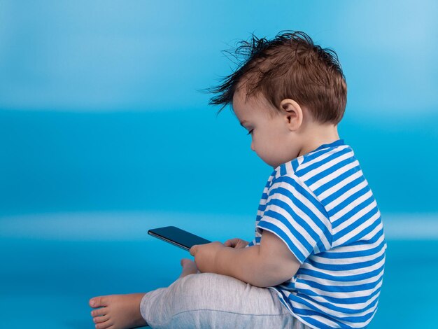 Photo infant holding smartphone addiction to gadgets from birth technology and children