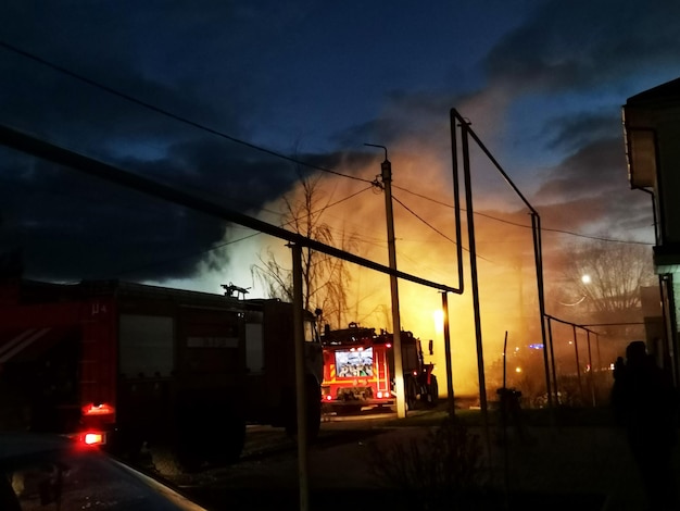 Inferno conflagration. House building on fire at night. Fireman fights fire.