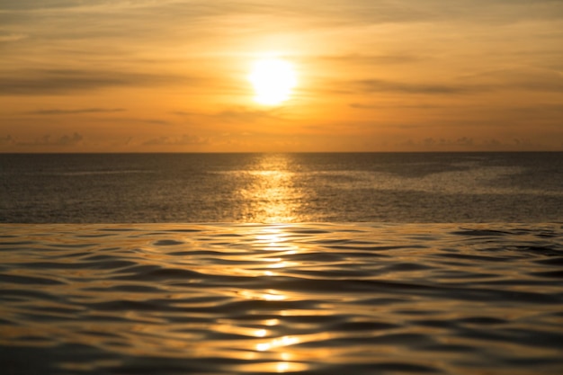 Infinity edge pool with sea underneath sunset