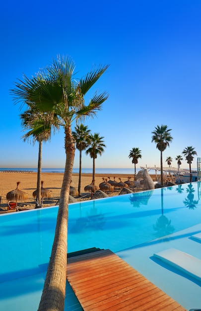 Infinity-zwembad op een strand met palmbomen