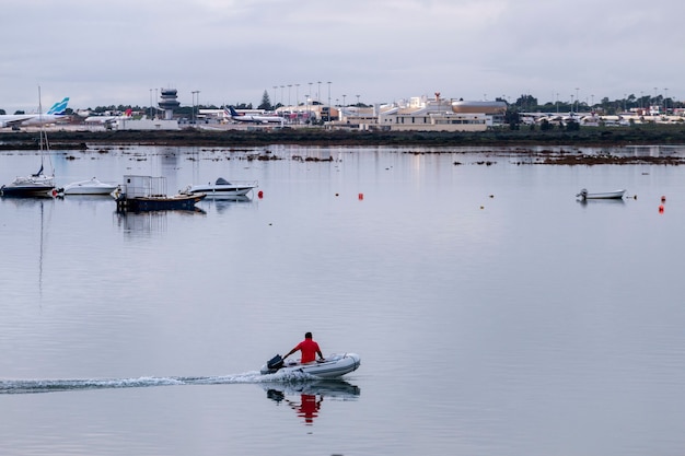 Inflatable boat cruises by on Ria Formosa marshlands with overview to the airport of Faro city, Portugal.