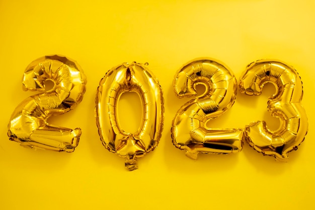 Inflatable golden balloons numbers on a yellow background happy new year flat lay copy space