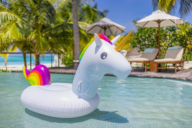 Inflatable pool toys at tropical resort pool, relaxing in\
infinity pool with ocean view under palms