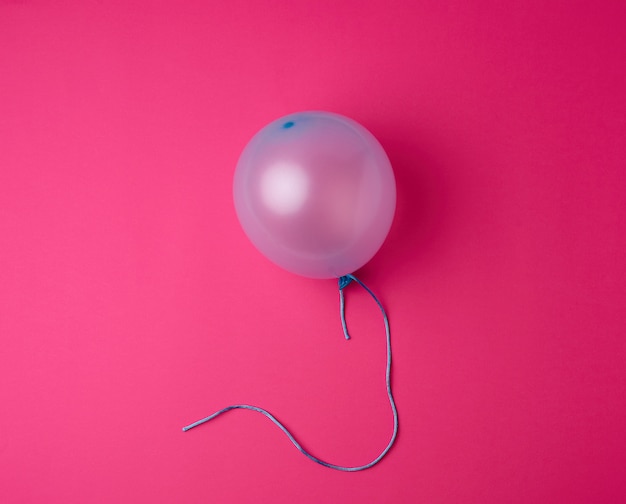 Inflated blue rubber balloon on pink 