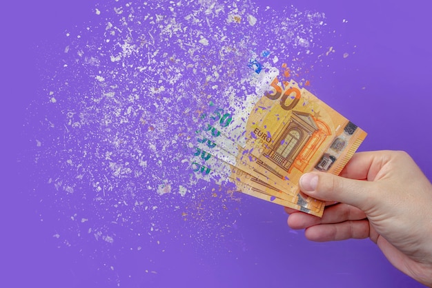 Inflation euro . Inflation in Europe, hyper inflation. Banner with purple background. Fifty euro banknotes sprayed in the hand of a man on a purple background.