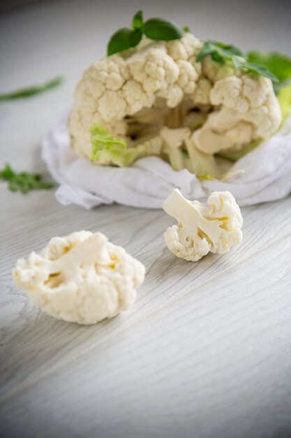 Inflorescences of small raw cauliflower on a light wooden table