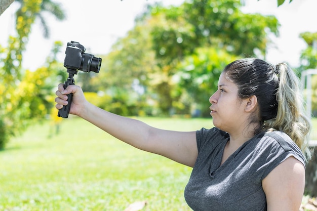 Foto ragazza influencer che alza la mano tenendo la fotocamera mentre registra un video vlog per le sue reti