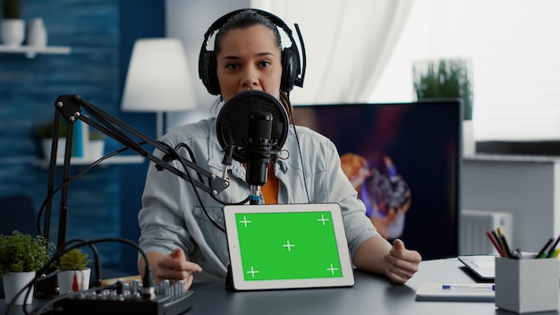 Influencer in studio die product promoot op tablet met groen scherm. Maker van sociale media-inhoud die touchscreen-apparaat aanbeveelt met Chromakey met geïsoleerde achtergrond en mockup-sjabloon