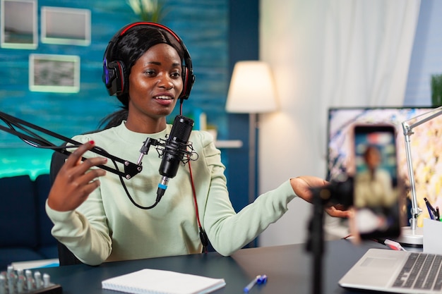 Influencer making online internet content for web subscribers in home podcast studio. Speaking during livestreaming, blogger discussing in podcast wearing headphones.