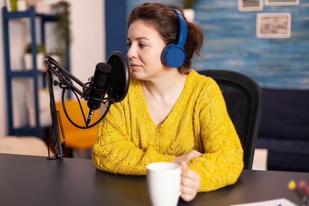 Influencer met koptelefoon die nieuwe podcastseries opneemt voor publiek. On-air online productie internetuitzending show host streaming live-inhoud voor digitale sociale media met behulp van internetweb.