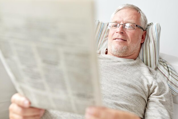 information, people, and mass media concept - close up of senior man reading newspaper at home