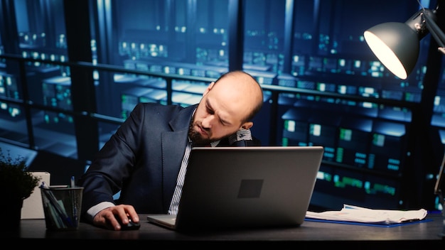 Information security officer finishing digitalization work in professional data center with mainframe servers. Male technician working in digital storage server room with artificial intelligence.