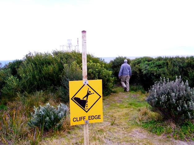 Photo information sign against man walking amidst plants