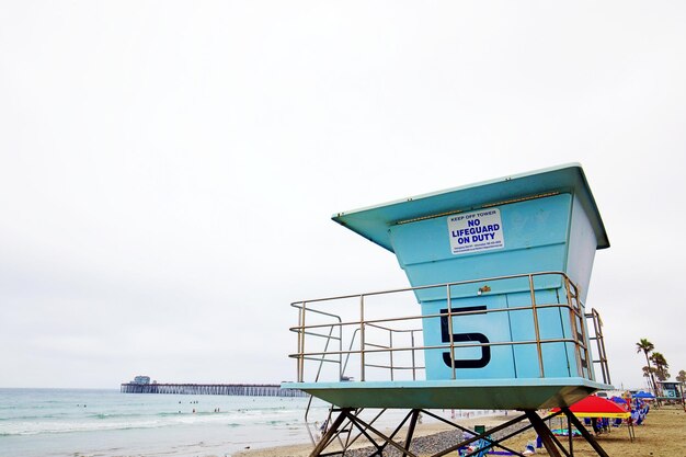 Photo information sign on beach against sky