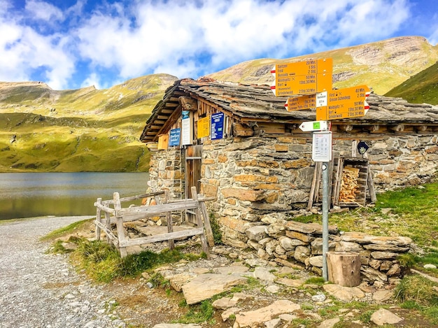 Foto segno informativo vicino a una vecchia casa in pietra contro le montagne