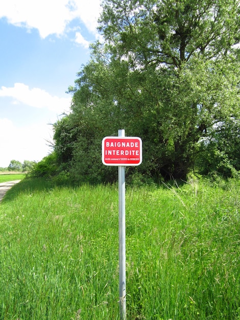 Photo information sign on grass against sky