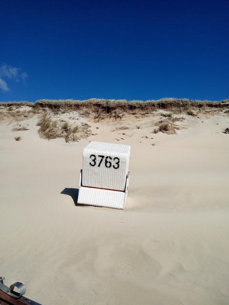 Information sign on sand at beach against clear blue sky