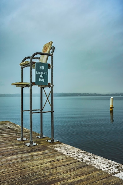 Foto segno informativo su palo di legno dal mare contro il cielo