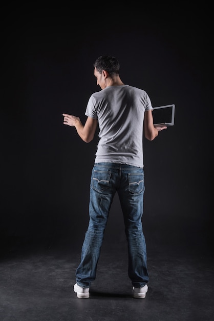 Informational space. Nice smart young man holding a laptop and standing in front of the computer while using computer technology