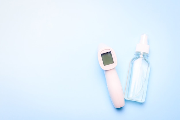 Infrared thermometer and antiseptic on a blue background