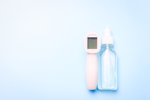 Infrared thermometer and antiseptic on a blue surface