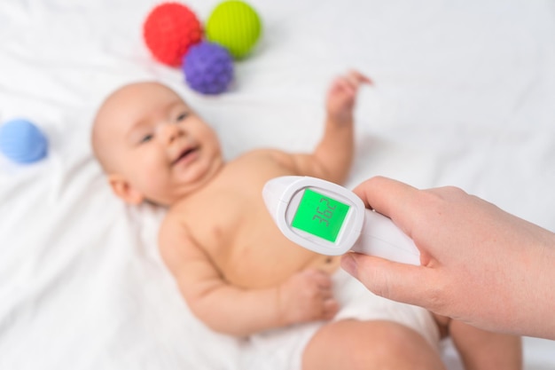 Infraroodthermometer in de hand van de arts die de temperatuur van een kind controleert. Selectieve focus