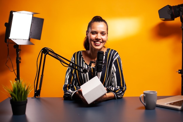 Infuencer presenteert weggeefactie aan camera tijdens het opnemen van vlog in thuisstudio