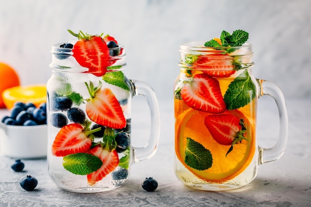 Infused detox water with blueberry strawberry orange and mint Ice cold summer cocktail or lemonade in glass mason jar