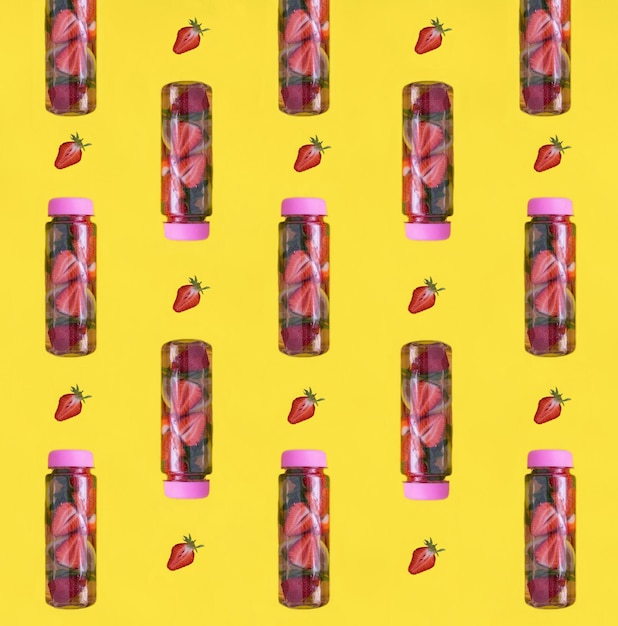 Infused or detox water with strawberry and lemon in the bottle on the yellow background Flat lay