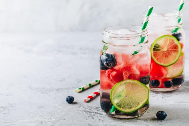 Infused detox water with watermelon lime and blueberry Ice cold summer cocktail or lemonade in glass mason jar