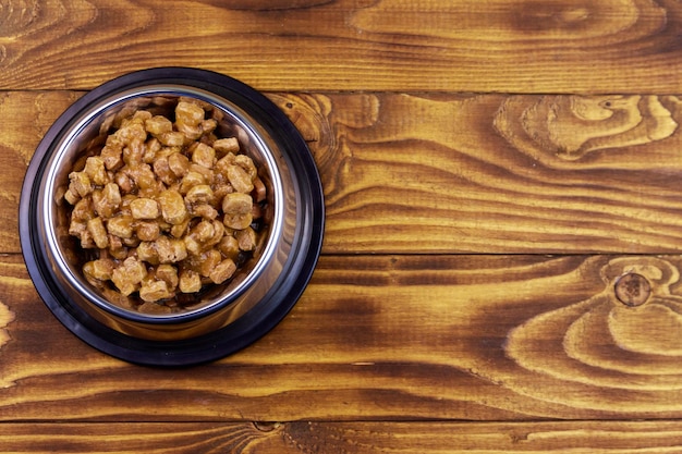 Ingeblikt voedsel voor katten of honden in metalen kom op houten vloer Bovenaanzicht