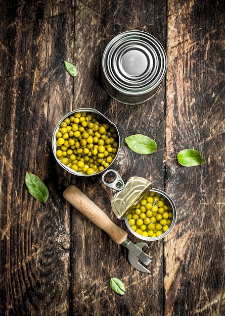 Ingeblikte groene erwten in een blikje met opener op een houten achtergrond