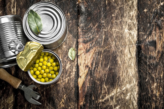 Foto ingeblikte groene erwten in een blikje met opener op een houten achtergrond