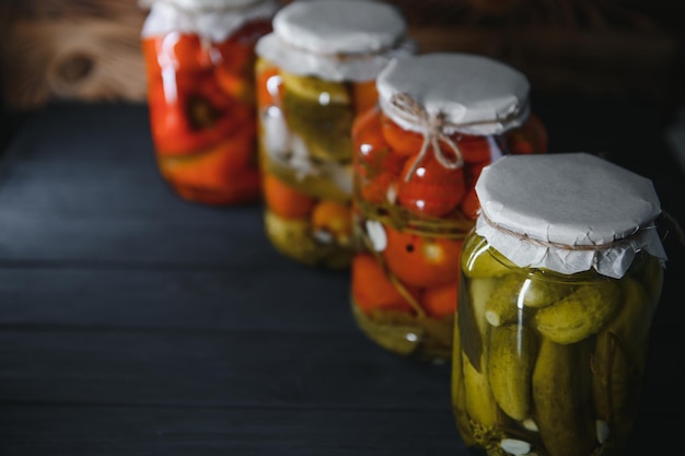 Ingeblikte komkommers en tomaten met ambachtelijke deksels op een houten achtergrond Komkommers en tomaten met plaats voor tekst Voorraden ingeblikt voedsel Oogstvoorraden voor de winter