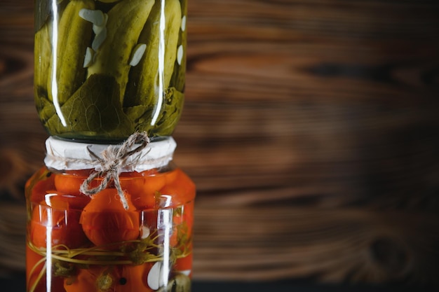 Ingeblikte komkommers en tomaten met ambachtelijke deksels op een houten achtergrond Komkommers en tomaten met plaats voor tekst Voorraden ingeblikt voedsel Oogstvoorraden voor de winter