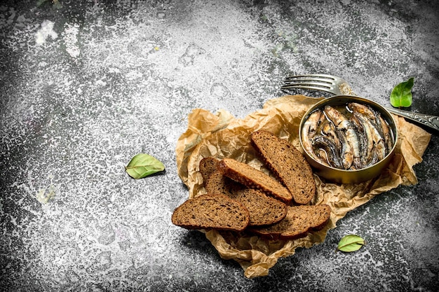 Ingeblikte sprot in blik met roggebrood. op een rustieke achtergrond.