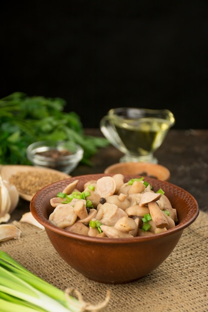 Ingelegde champignons in een kom op een donkere achtergrond. Champignons met kruiden en specerijen. Gefermenteerd voedsel. Ingemaakte groenten. Vegetarisch eten. Uitzicht van boven. Kopieer ruimte. Voedsel achtergrond.