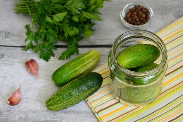 ingelegde komkommers in pot op keukentafel met knoflook en peterselie