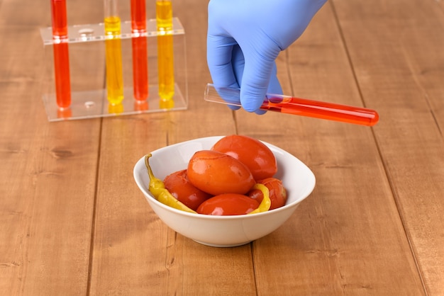 Ingelegde rode tomaten met Spaanse peper en laboratoriumglas met rode vloeistof.
