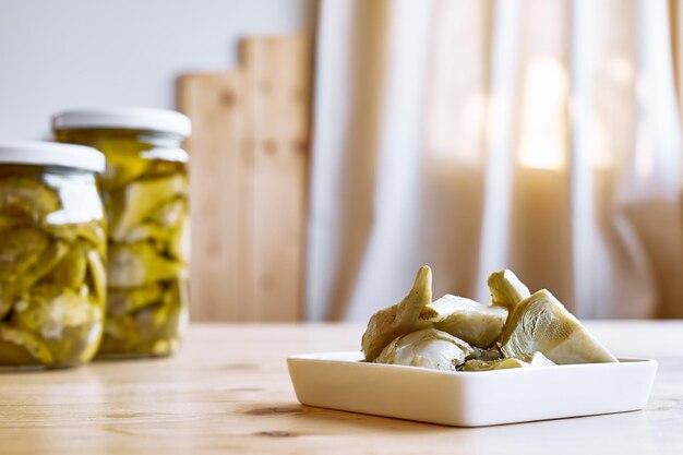 Ingemaakte artisjok met knoflook in witte plaat op houten tafel