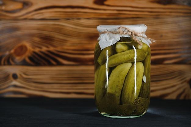 Ingemaakte augurken of komkommers in kom op houten rustieke tafel van bovenaf