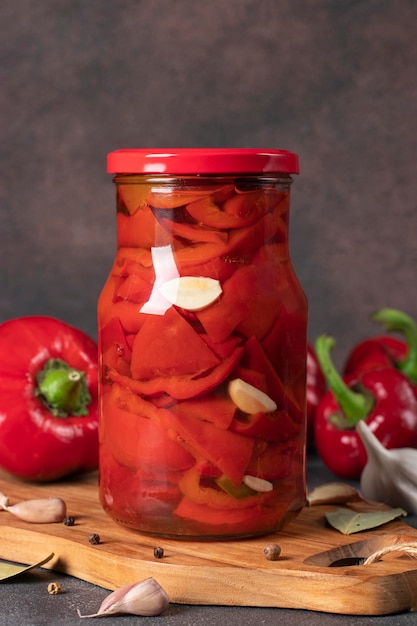 Foto ingemaakte paprika's met knoflook in glazen pot op bruine achtergrond verticaal formaat